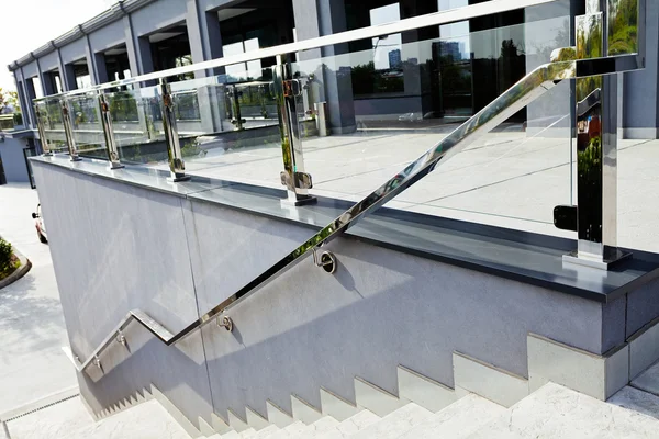 White stairs with metal and glass railing, infront business building