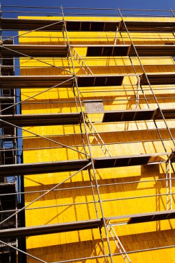 sarı koruyucu katranlı ve iskele üzerinde bir bina