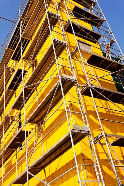 yellow protective tarpaulins and scaffolding on a building