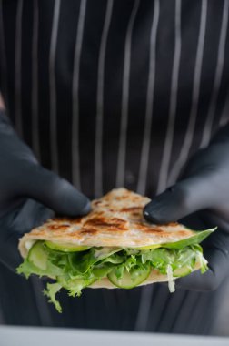 Şef elinde otlu bir ekmek tutuyor.