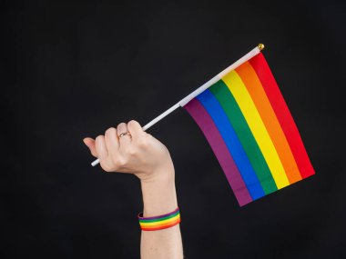 Evlilik yüzüklü kadın siyah arka planda gökkuşağı bayrağı taşıyor.