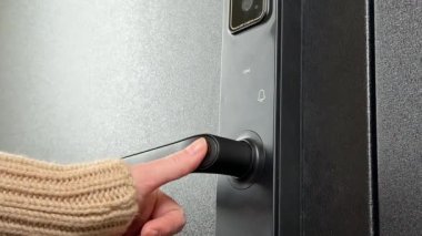 Bir kadın dijital tuş takımı ve biyometrik parmak izi erişimiyle modern bir akıllı kapı kilidi açar.
