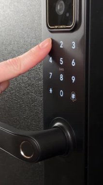 Bir kadın, dijital bir tuş takımı kullanarak modern bir akıllı kapı kilidi açar.