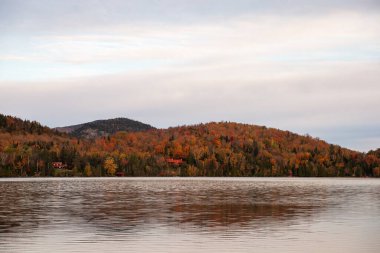 Sonbaharda arka planda dağlar olan bir göl manzarası..