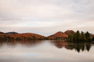 Quebec, Kanada 'da bulunan ve arka planda dağlar bulunan bir göl içeren pitoresk bir sonbahar manzarası..