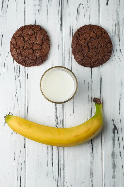 Funny face of the banana, milk and cookies — Stock Photo, Image