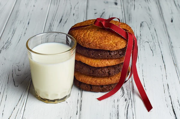 Стакан молока и печенья, завязанные красной лентой . — стоковое фото