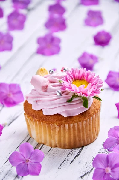 Güzel yumuşak kek krem ve bir sürü canlı pembe / mor çiçekler.