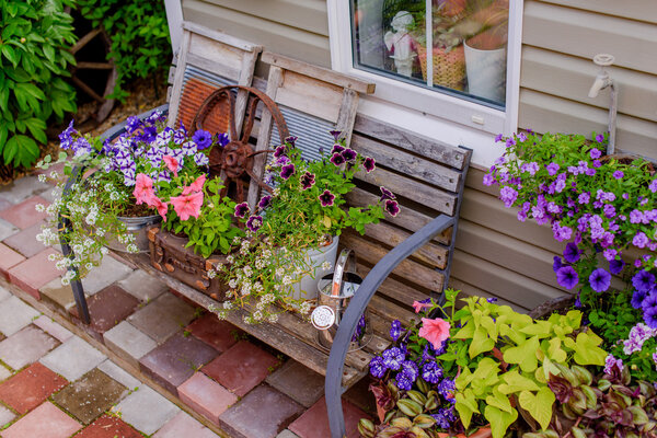 Beautifully decorated porch of a private house, colorful flowers in large clay pots, vintage bench, vintage inventory.