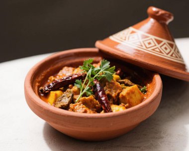 Otantik Fas tagini; zengin baharatlar, taze et, sebze ve otlarla dolu kil kapta servis edilir. Geleneksel Maghrebi mutfağı, Kuzey Afrika konfor gıdası ve ticari kullanım için klasik kültürel yemek konsepti sergilenir..