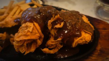 Bol tuzlu sos soslu kızarmış tavuk, yanında patates kızartması ve karışık sebze, restoran menüsü ve yemek reklamı için mükemmel bir konfor yemeği.