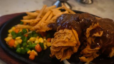 Bol tuzlu sos soslu kızarmış tavuk, yanında patates kızartması ve karışık sebze, restoran menüsü ve yemek reklamı için mükemmel bir konfor yemeği.