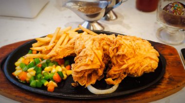 Bol tuzlu sos soslu kızarmış tavuk, yanında patates kızartması ve karışık sebze, restoran menüsü ve yemek reklamı için mükemmel bir konfor yemeği.