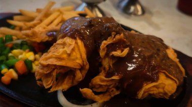 Bol tuzlu sos soslu kızarmış tavuk, yanında patates kızartması ve karışık sebze, restoran menüsü ve yemek reklamı için mükemmel bir konfor yemeği.