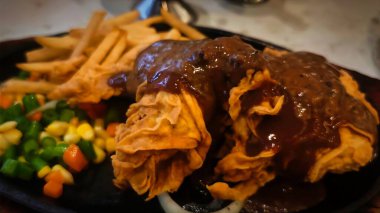 Bol tuzlu sos soslu kızarmış tavuk, yanında patates kızartması ve karışık sebze, restoran menüsü ve yemek reklamı için mükemmel bir konfor yemeği.