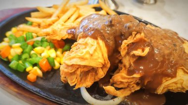 Bol tuzlu sos soslu kızarmış tavuk, yanında patates kızartması ve karışık sebze, restoran menüsü ve yemek reklamı için mükemmel bir konfor yemeği.