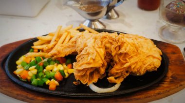 Bol tuzlu sos soslu kızarmış tavuk, yanında patates kızartması ve karışık sebze, restoran menüsü ve yemek reklamı için mükemmel bir konfor yemeği.