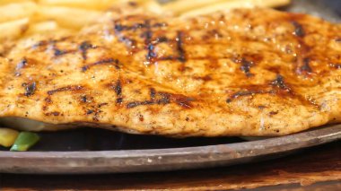 Kızarmış patates kızartması ve renkli taze sebzelerle servis edilen sulu ızgara tavuk bifteği restoran menüsü, yemek reklamı ve ticari mutfak içeriği için mükemmel.