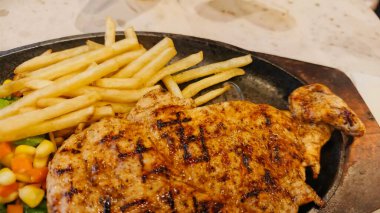 Kızarmış patates kızartması ve renkli taze sebzelerle servis edilen sulu ızgara tavuk bifteği restoran menüsü, yemek reklamı ve ticari mutfak içeriği için mükemmel.