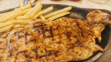 Kızarmış patates kızartması ve renkli taze sebzelerle servis edilen sulu ızgara tavuk bifteği restoran menüsü, yemek reklamı ve ticari mutfak içeriği için mükemmel.