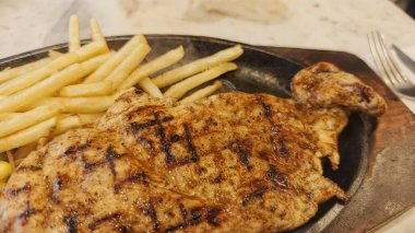 Kızarmış patates kızartması ve renkli taze sebzelerle servis edilen sulu ızgara tavuk bifteği restoran menüsü, yemek reklamı ve ticari mutfak içeriği için mükemmel.