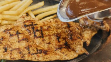 Kızarmış patates kızartması ve renkli taze sebzelerle servis edilen sulu ızgara tavuk bifteği restoran menüsü, yemek reklamı ve ticari mutfak içeriği için mükemmel.