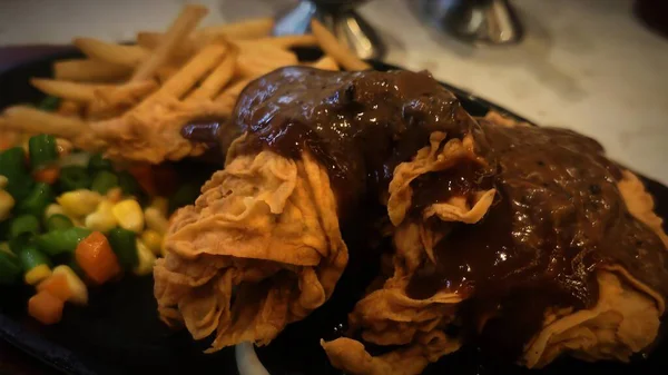 Bol tuzlu sos soslu kızarmış tavuk, yanında patates kızartması ve karışık sebze, restoran menüsü ve yemek reklamı için mükemmel bir konfor yemeği.