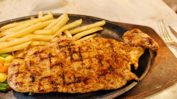 Kızarmış patates kızartması ve renkli taze sebzelerle servis edilen sulu ızgara tavuk bifteği restoran menüsü, yemek reklamı ve ticari mutfak içeriği için mükemmel.