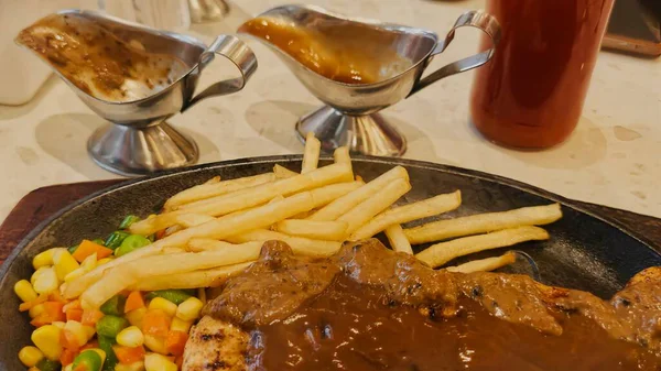 Kızarmış patates kızartması ve renkli taze sebzelerle servis edilen sulu ızgara tavuk bifteği restoran menüsü, yemek reklamı ve ticari mutfak içeriği için mükemmel.