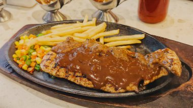 Kızarmış patates kızartması ve renkli taze sebzelerle servis edilen sulu ızgara tavuk bifteği restoran menüsü, yemek reklamı ve ticari mutfak içeriği için mükemmel.