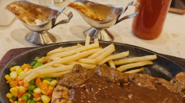 Kızarmış patates kızartması ve renkli taze sebzelerle servis edilen sulu ızgara tavuk bifteği restoran menüsü, yemek reklamı ve ticari mutfak içeriği için mükemmel.