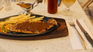 Kızarmış patates kızartması ve renkli taze sebzelerle servis edilen sulu ızgara tavuk bifteği restoran menüsü, yemek reklamı ve ticari mutfak içeriği için mükemmel.