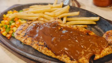 Kızarmış patates kızartması ve renkli taze sebzelerle servis edilen sulu ızgara tavuk bifteği restoran menüsü, yemek reklamı ve ticari mutfak içeriği için mükemmel.