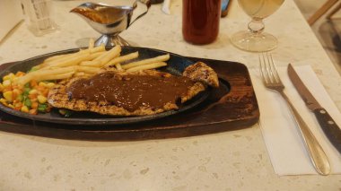 Kızarmış patates kızartması ve renkli taze sebzelerle servis edilen sulu ızgara tavuk bifteği restoran menüsü, yemek reklamı ve ticari mutfak içeriği için mükemmel.