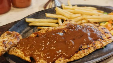 Kızarmış patates kızartması ve renkli taze sebzelerle servis edilen sulu ızgara tavuk bifteği restoran menüsü, yemek reklamı ve ticari mutfak içeriği için mükemmel.