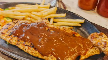 Kızarmış patates kızartması ve renkli taze sebzelerle servis edilen sulu ızgara tavuk bifteği restoran menüsü, yemek reklamı ve ticari mutfak içeriği için mükemmel.