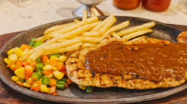 Kızarmış patates kızartması ve renkli taze sebzelerle servis edilen sulu ızgara tavuk bifteği restoran menüsü, yemek reklamı ve ticari mutfak içeriği için mükemmel.