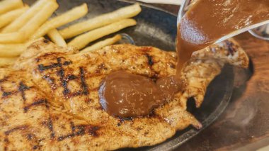 Kızarmış patates kızartması ve renkli taze sebzelerle servis edilen sulu ızgara tavuk bifteği restoran menüsü, yemek reklamı ve ticari mutfak içeriği için mükemmel.