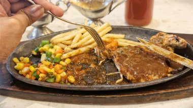 Kızarmış patates kızartması ve renkli taze sebzelerle servis edilen sulu ızgara tavuk bifteği restoran menüsü, yemek reklamı ve ticari mutfak içeriği için mükemmel.