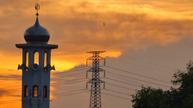 Gün batımında caminin minare silueti dramatik gökyüzü manzarasıyla İslami mimari güç hatlarını ve altın bulutları Din Kültürü ve Şehir Arkaplanı için mükemmel