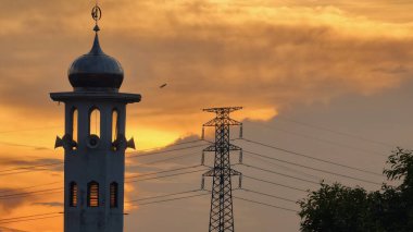 Gün batımında caminin minare silueti dramatik gökyüzü manzarasıyla İslami mimari güç hatlarını ve altın bulutları Din Kültürü ve Şehir Arkaplanı için mükemmel