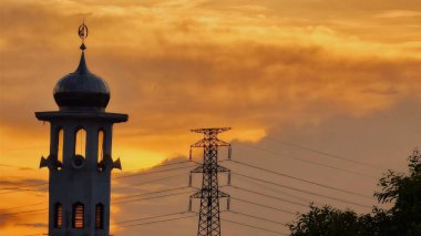 Gün batımında caminin minare silueti dramatik gökyüzü manzarasıyla İslami mimari güç hatlarını ve altın bulutları Din Kültürü ve Şehir Arkaplanı için mükemmel