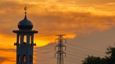 Gün batımında caminin minare silueti dramatik gökyüzü manzarasıyla İslami mimari güç hatlarını ve altın bulutları Din Kültürü ve Şehir Arkaplanı için mükemmel