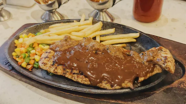 Kızarmış patates kızartması ve renkli taze sebzelerle servis edilen sulu ızgara tavuk bifteği restoran menüsü, yemek reklamı ve ticari mutfak içeriği için mükemmel.