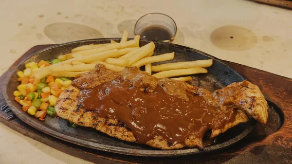 Kızarmış patates kızartması ve renkli taze sebzelerle servis edilen sulu ızgara tavuk bifteği restoran menüsü, yemek reklamı ve ticari mutfak içeriği için mükemmel.