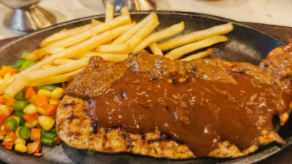 Kızarmış patates kızartması ve renkli taze sebzelerle servis edilen sulu ızgara tavuk bifteği restoran menüsü, yemek reklamı ve ticari mutfak içeriği için mükemmel.