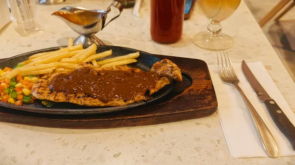 Kızarmış patates kızartması ve renkli taze sebzelerle servis edilen sulu ızgara tavuk bifteği restoran menüsü, yemek reklamı ve ticari mutfak içeriği için mükemmel.