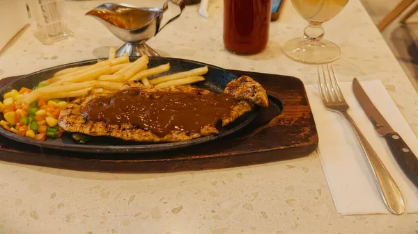 Kızarmış patates kızartması ve renkli taze sebzelerle servis edilen sulu ızgara tavuk bifteği restoran menüsü, yemek reklamı ve ticari mutfak içeriği için mükemmel.