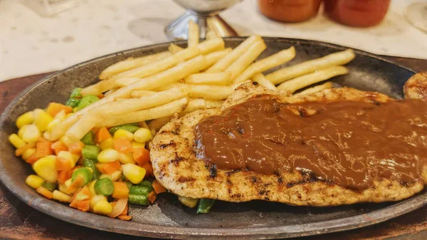 Kızarmış patates kızartması ve renkli taze sebzelerle servis edilen sulu ızgara tavuk bifteği restoran menüsü, yemek reklamı ve ticari mutfak içeriği için mükemmel.