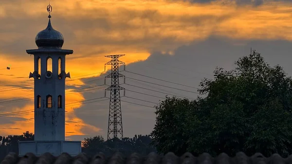 Gün batımında caminin minare silueti dramatik gökyüzü manzarasıyla İslami mimari güç hatlarını ve altın bulutları Din Kültürü ve Şehir Arkaplanı için mükemmel